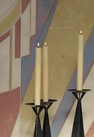 Brennende Kerzen vor einer farbigen Wand